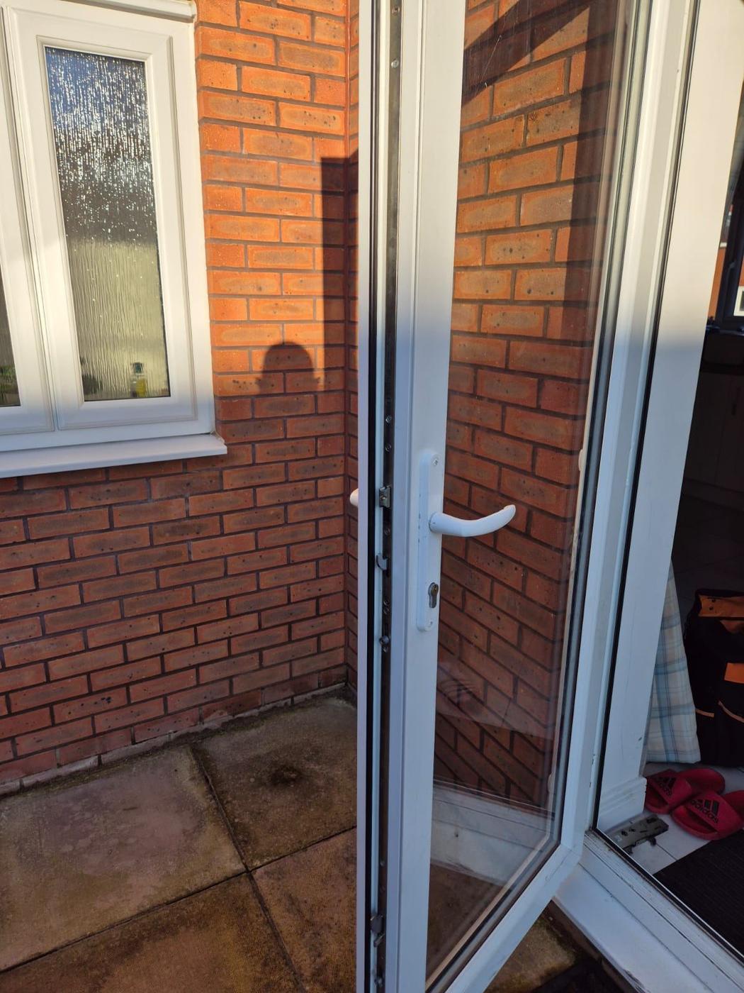 Open uPVC door with white frame and hardware visible, brick wall in background — uPVC door repair completed in Redditch.
