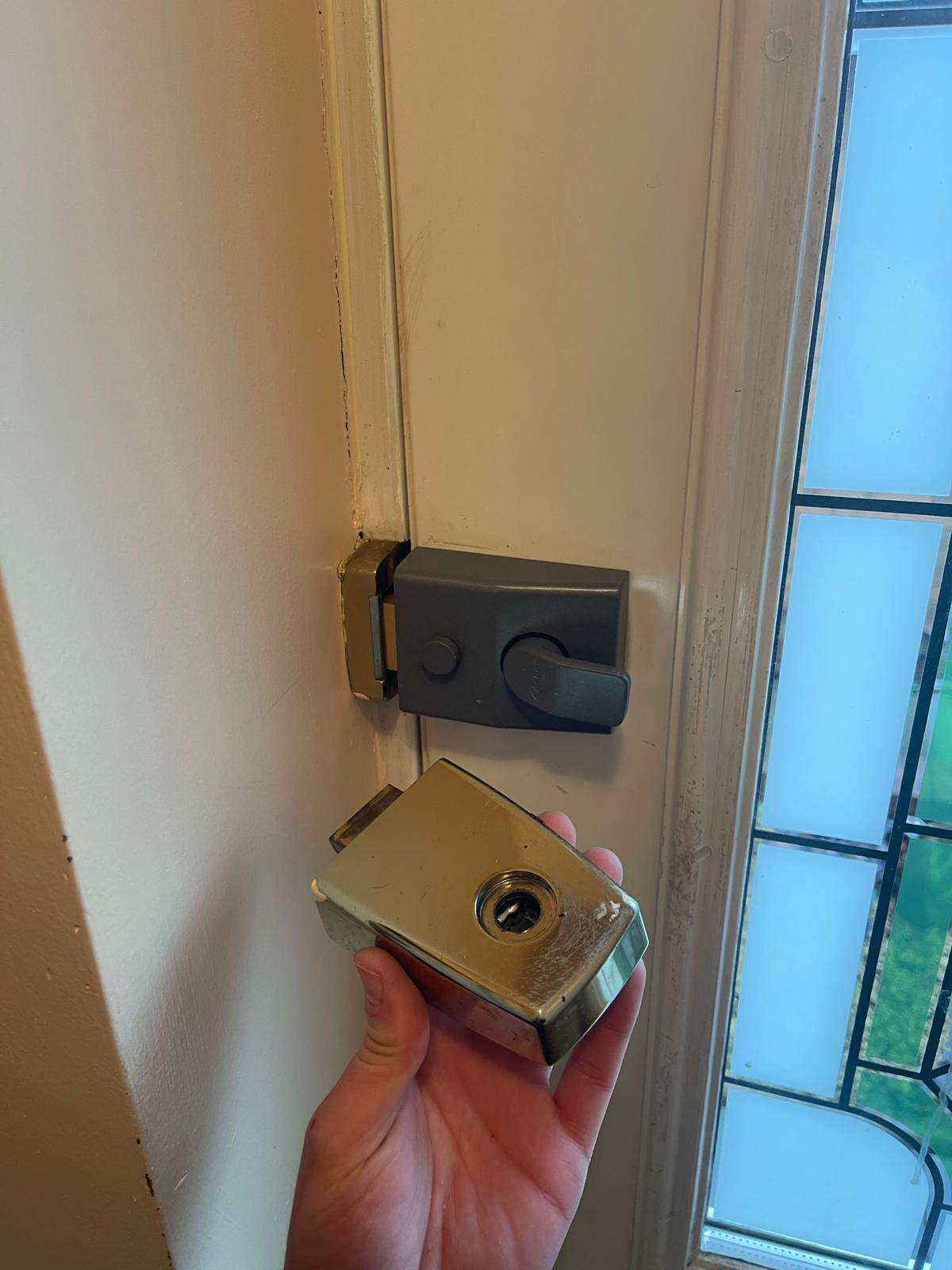 Newly installed Yale night latch on a door, replacement cylinder held in the engineer's hand — emergency entry resolved.