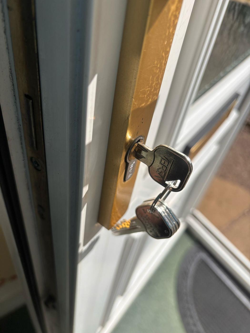 New key turned in a gold Yale handle on a white uPVC door — lock change supplied and fitted.